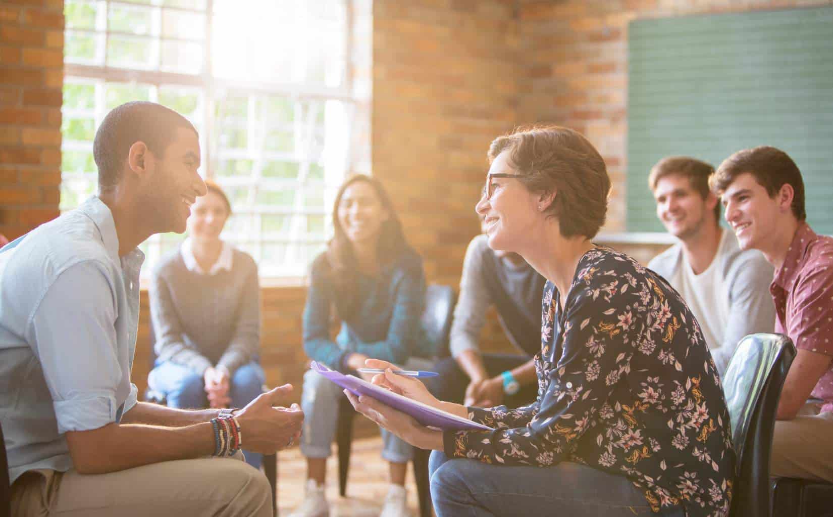 Therapist engaging with group of young adults in a supportive setting.