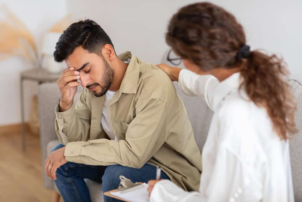Man receiving comfort from a therapist during co-occurring depression treatment in Massachusetts.