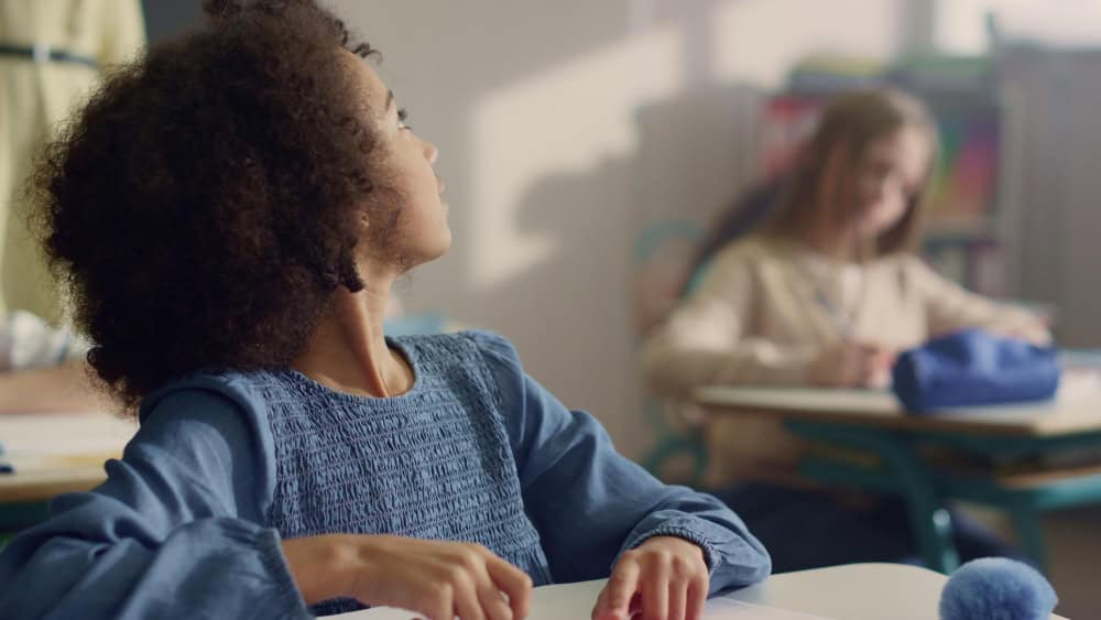 Student raising her hand during class while receiving academic support as part of addiction treatment for college students in Massachusetts.