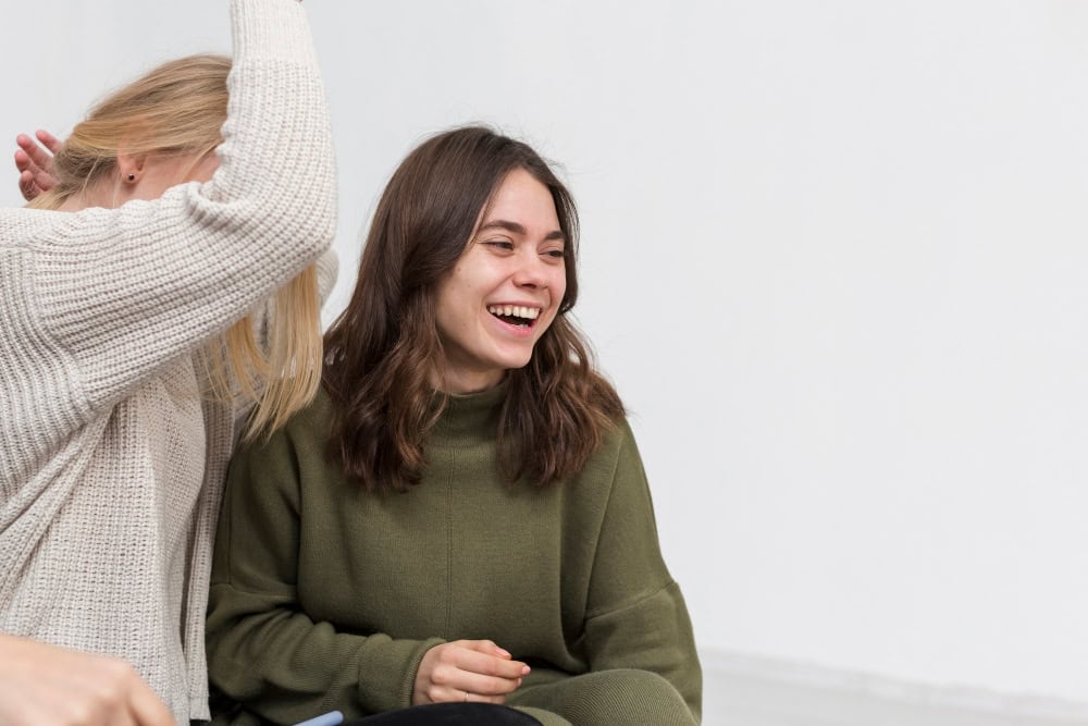 Two women smiling during a group therapy session at an alcohol rehab in Hingham, MA.