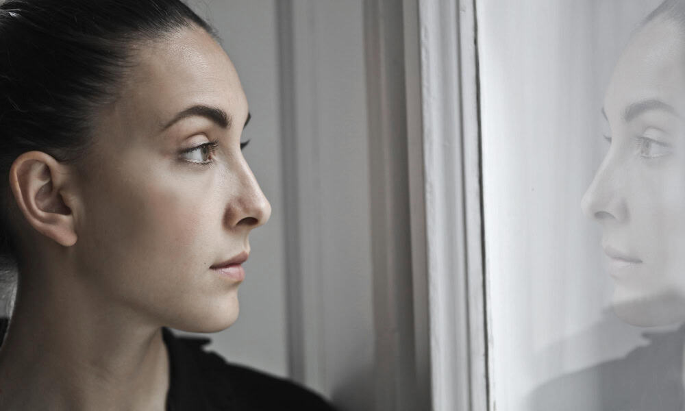 Young woman looking through a window while seeking support for dual diagnosis borderline personality disorder in Massachusetts.