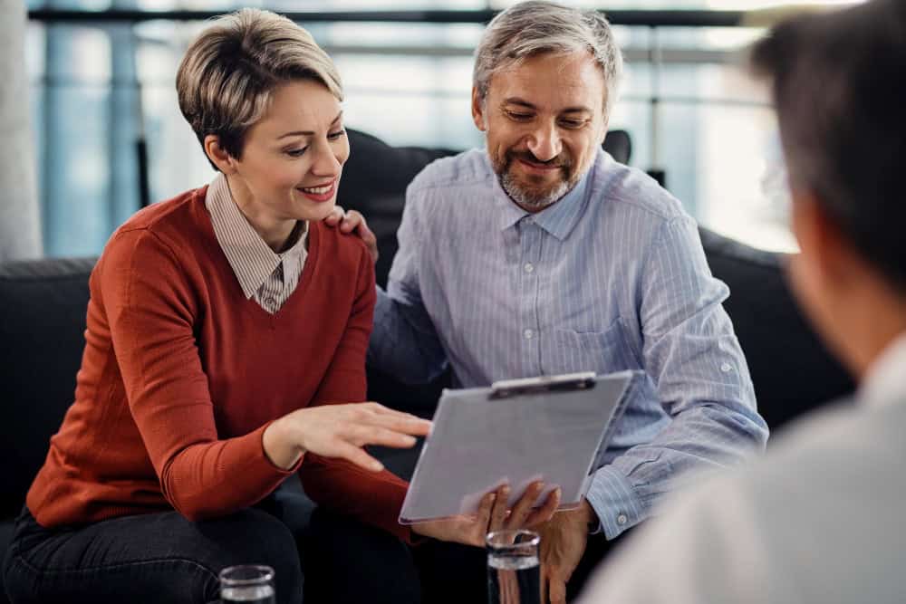Happy couple reviewing an agreement while exploring rehabs that take Aetna insurance.