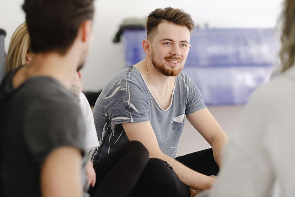 Smiling young adult speaking with a therapist during drug rehab for young adults.