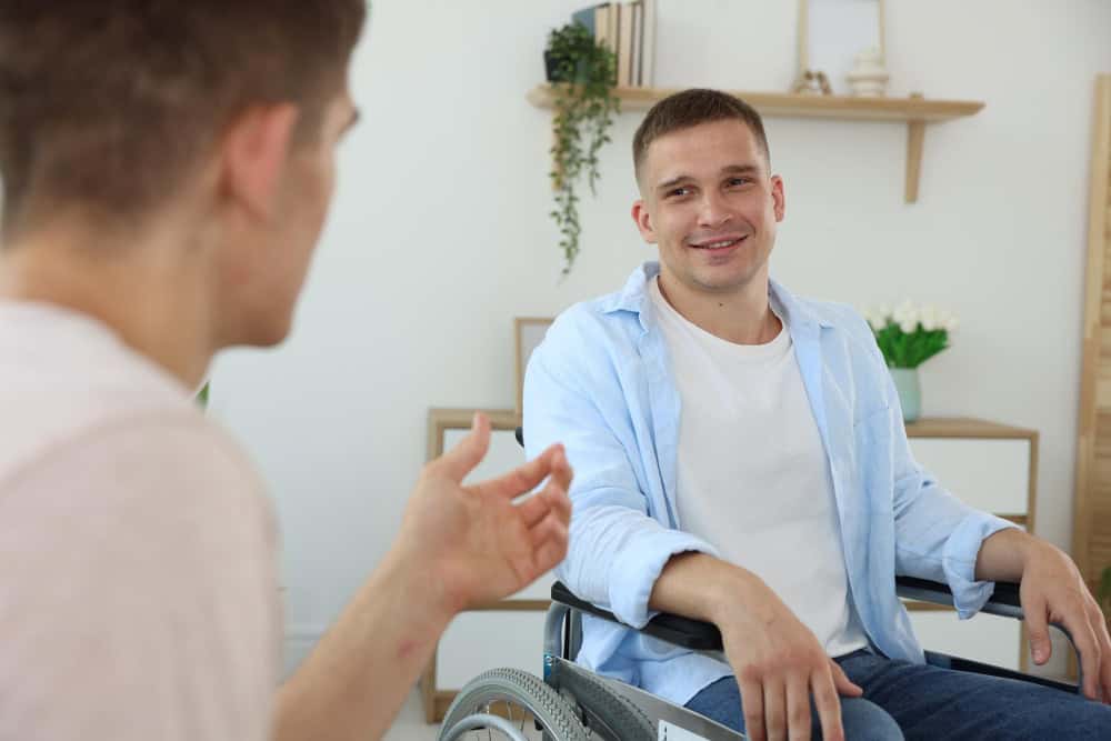 Young man in a wheelchair speaking with a therapist during young adult rehab in Massachusetts.